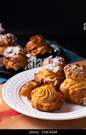 Lebensmittelkonzept hausgemachte Caramel Choux a la Cream oder Choux Cream Puffs auf dunklem Hintergrund mit Kopierfläche Stockfoto