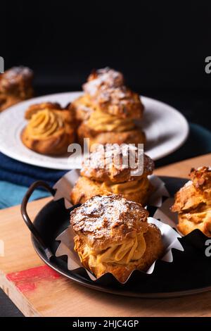 Lebensmittelkonzept hausgemachte Caramel Choux a la Cream oder Choux Cream Puffs auf dunklem Hintergrund mit Kopierfläche Stockfoto