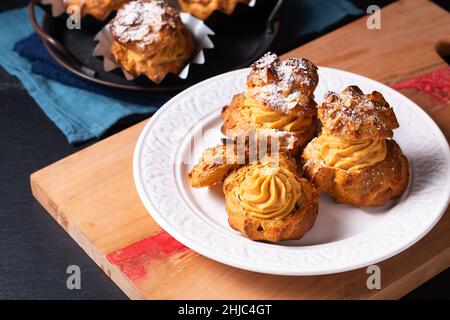 Lebensmittelkonzept hausgemachte Caramel Choux a la Cream oder Choux Cream Puffs auf dunklem Hintergrund mit Kopierfläche Stockfoto