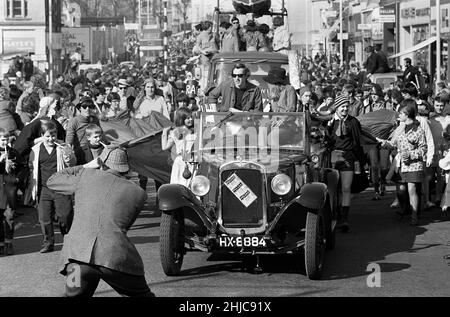 Die Rag-Prozession der Universität Bristol 1969 wird von einem offenen Oldtimer mit Rag Queen und Rag Chairman geleitet. Der Austin 12 von 1930s leitete eine Parade von Festwagen an, die von Studenten geschmückt wurden und am 8. März 1969 vom Parkplatz der Clifton Down Station aus aufmarschierten, die Park Street entlang zur Baldwin Street führten, dann weiter durch Broadmead, bevor es entlang der Lower und Upper Maudlin Street und der Park Row zurückging. Tausende Zuschauer säumten die Straßen und Tausende von Pfund wurden für wohltätige Zwecke gesammelt. Stockfoto