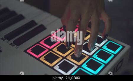 Drum Machine im Nachtclub spielt Live Set. Lager. Finger klopfen auf Trommelbeläge an einem digitalen Beatmaker in Nahaufnahme. DJ beginnt mit der Wiedergabe der im eingestellten Musik Stockfoto