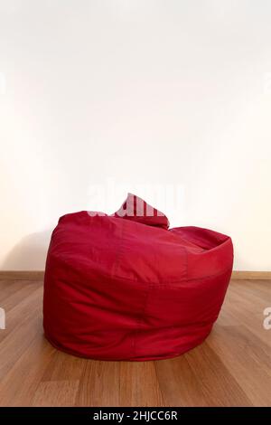 Leere rote Stuhltasche im Wohnzimmer mit Holzboden. Komfortable moderne Innenmöbel. Stockfoto