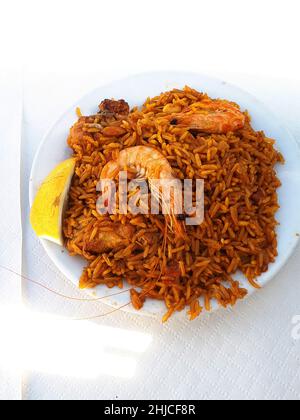 Kochen einer Paella in einer riesigen Eisenpfanne am Strand von Burriana in Nerja an der Costa del Sol in Südspanien. Sie wird aus Reis, Huhn und Garnelen hergestellt Stockfoto