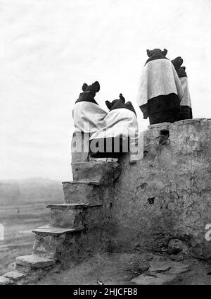 Edward S Curtis Foto mit dem Titel Watching the Dancers - vier Hopi-Mädchen auf einem Dach beobachten einen Pueblo-Tanz unten - Walpi Pueblo, Arizona 1906 Stockfoto