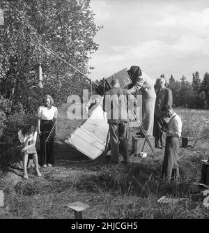 Dreharbeiten in der 1940s. Das Filmteam am Set des Films Ungt blod und die Schauspielerinnen Brita Holmberg und Agneta Lagerfelt in einer Outdoor-Szene. Rechts der Regisseur Ivar Johansson. Der Filmfotograf hat den Teil der Filmkamera, in dem er die Szene sieht, wegen des intensiven Sonnenlichts bedeckt, den er Karl-Erik Alberts nennt. Ort ist Sturehov im Süden von Stockholm. Schweden 1943 Kristoffersson Ref. E82-6 Stockfoto