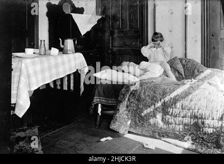 Eine Frau, die während der Spanischen Grippepandemie zu Hause an Influenza erkrankt war, November 1918. Originalunterschrift: „Ihre Schwester hatte Mrs. Brown fast eine Woche lang nicht gesehen, und mit Mr. Brown, einem Soldaten in Frankreich, wurde sie so besorgt, dass sie den Hausdienst des Roten Kreuzes anrief, der gerade rechtzeitig eintraf, um Mrs. Brown aus den Klauen der Grippe zu retten.“ Die spanische Grippe von 1918 bis 1920 war eine ungewöhnlich tödliche Influenza-Pandemie, die durch das H1N1-Influenza-A-Virus verursacht wurde. Stockfoto