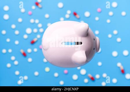 Pink Piggy Bank auf dem blauen Hintergrund von Pillen und Tabletten, Draufsicht. Coronavirus, 2019-nCoV. Medizin- und Gesundheitskonzept Stockfoto