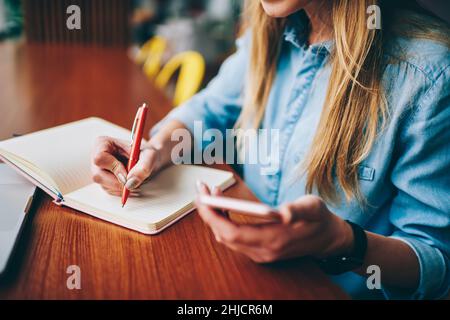 Studentin macht Notizen im Notizbuch Stockfoto