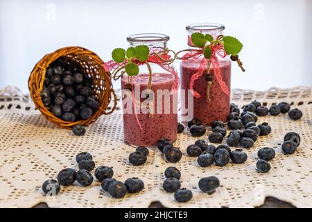 Zwei Flaschen mit Bändern aus köstlichem, gesundem Joghurt, Smoothie und Heidelbeer-Smoothie Stockfoto