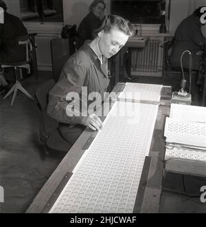 Herstellung von Briefmarken in der 1950s. Eine junge Frau bei den schwedischen Briefmarkendrucken der schwedischen Post geht sorgfältig durch die neu gedruckten Gustaf VI Adolf-Marken, um Defektmuster zu finden und zu entfernen. Das Briefmarkenblatt wird später in Rollen mit 100 oder 500 Marken umgewandelt. Schweden 1951 Kristoffersson Ref. bc45-7 Stockfoto