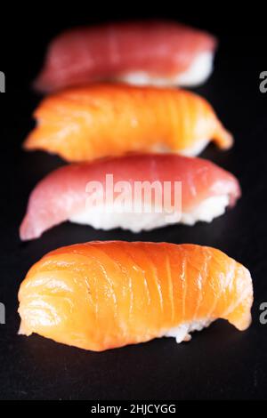 Eine Platte mit Thunfisch und Lachs Nigiri. Sushi-Sorten, das Gericht stammt aus Japan und besteht aus dünn geschnittenem rohem Fisch, der über weißem Reis mit gemischtem Witz serviert wird Stockfoto