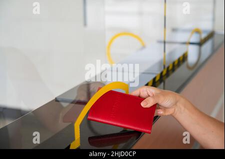Gesichtslose Frau, die ihren Pass am Check-in-Schalter am Flughafen ausgibt. Stockfoto