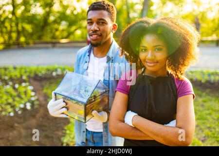 afroamerikanisches Paar, das am sonnigen Frühlingstag bei Sonnenuntergang im Freien gärtet Stockfoto