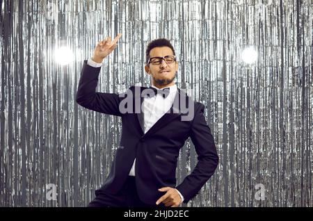 Fröhlicher, lustiger junger Mann in elegantem Anzug und Fliege, tanzt und hat Spaß auf einer Party Stockfoto