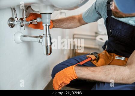 Männliche Klempner Hände Reparatur Rohr unter Waschbecken Stockfoto
