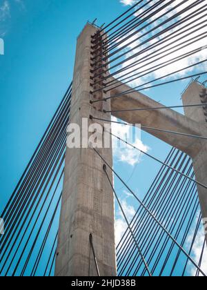 Detail der Stahlseile und des Betonturms einer Seilbrücke an einem sonnigen Tag. Stockfoto