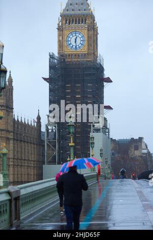 Der Elizabeth Tower, der gemeinhin als Big Ben bekannt ist, wird als Fußgänger angesehen, der einen Regenschirm mit der Unionsflagge auf der Westminster Bridge im Zentrum Londons hält. Stockfoto