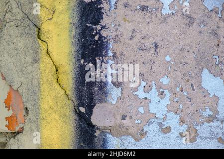 Alte gelb-blau-schwarze Farbe mit Rissen auf roten Ziegelwänden als Hintergrund, Textur, selektiver Fokus Stockfoto