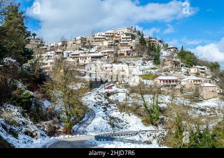 Malerisches Snowy Village in Upper Vlasia in Griechenland. Traditionelle Häuser in amphitheatralischer Architektur an einem sonnigen Wintertag. Stockfoto