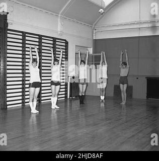 1960s, historisch, Jugendclub, in einer Sporthalle, some Teenager-Mädchen in Turnhalle Kleidung, Tops und Shorts, und Pumpen, Stretching-Übungen, Schottland, VEREINIGTES KÖNIGREICH. In dieser Zeit spielten lokale Jugendclubs, ähnlich wie die Pfadfinder und Mädchenführer, eine wichtige Rolle in der Gemeinschaft, indem sie jungen Menschen Aktivitäten im Innen- und Außenbereich zur Verbesserung ihrer Gesundheit und ihres Selbstwertgefühls zur Verfügung gestellt haben. Stockfoto