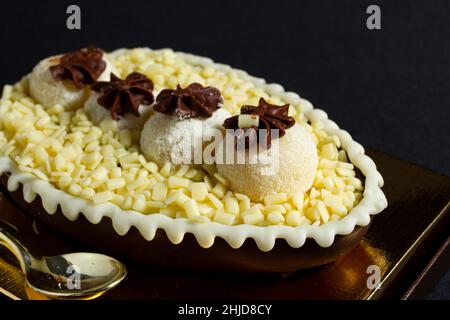 Brasilianisches osterei gefüllt mit weißer granulierter Schokolade und Creme, schmeckte mit einem Löffel. Ostertradition in Brasilien Stockfoto