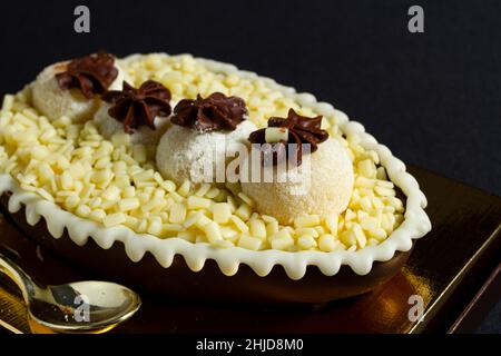 Brasilianisches osterei gefüllt mit weißer granulierter Schokolade und Creme, schmeckte mit einem Löffel. Ostertradition in Brasilien Stockfoto