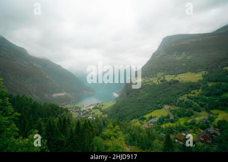 Blick auf das Tal mit türkisfarbenem See und das Geiranger kleine Touristendorf in Norwegen Stockfoto