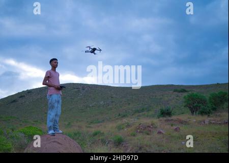 Teenager mit Drohne vor ihm schweben gesehen Stockfoto