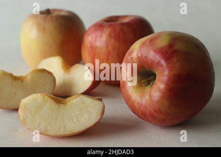 Eine Ernte aus roten frischen Äpfeln, die zufällig zusammen mit saftigen Scheiben gelegt wird. Aufgenommen auf weißem Hintergrund. Stockfoto