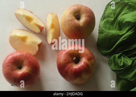 Eine Ernte aus roten frischen Äpfeln, die zufällig zusammen mit saftigen Scheiben gelegt wird. Aufgenommen auf weißem Hintergrund. Stockfoto