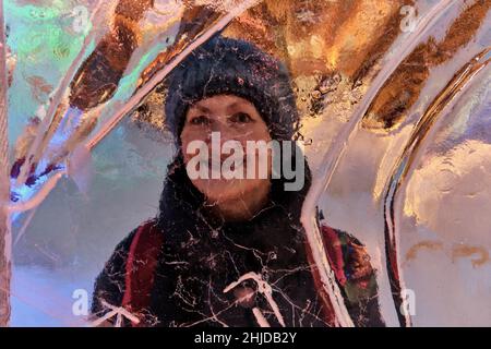Kreatives Winterporträt über der Eiswand der glücklichen lächelnden älteren Frau. Stockfoto