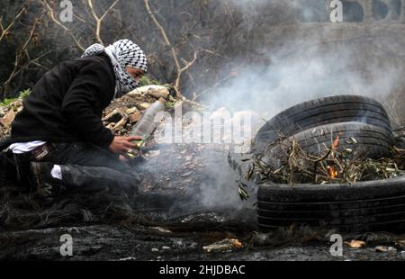 Nablus, Palästina. 28th Januar 2022. Ein palästinensischer Demonstranten verbrennt während einer Demonstration gegen israelische Siedlungen im Dorf Kafr Qaddum in der Nähe der Stadt Nablus im Westjordanland Reifen. (Foto von Nasser Ishtayeh/SOPA Images/Sipa USA) Quelle: SIPA USA/Alamy Live News Stockfoto