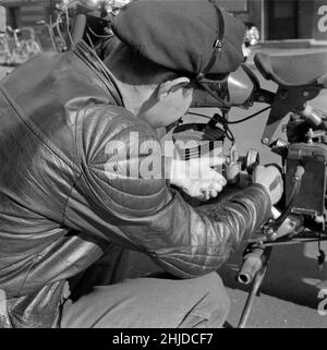 Motorradfahrer in der 1950s. Ein junger Mann an seinem Motorrad beugte sich nach unten, um sich etwas im Motor anzusehen. Schweden 1951 Stockfoto