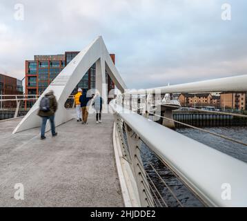 Menschen (nicht erkennbar an Bewegungsunschärfen), die die Tradeston Footbridge überqueren, auch bekannt als die quicklige Brücke über den Fluss Clyde in Glasgow Stockfoto