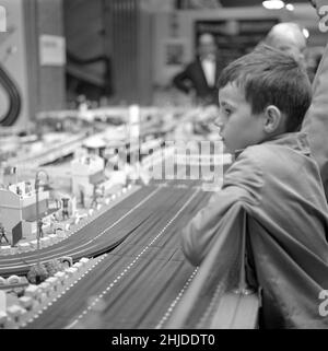 Spielzeug in der 1960s. Ein Junge fasziniert von einer Miniatur-Rennstrecke von Scalextric. Man konnte Autos mit einer Fernbedienung fahren und gegeneinander antreten, da es das war, worum es im Spiel ging. Schweden 1962 Stockfoto