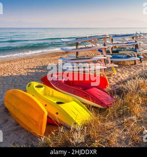 Kajaks und Surfbretter wurden am Morgen eines sonnigen Tages am Strand gelagert. Stockfoto