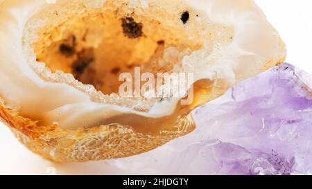 Citrin-Geode mit Kristallen und purpurfarbener Amethyst-Makrofotografie. Citrin und Amethyst auf weißem Hintergrund. Die Verwendung von Mineralien und Halbedelsteinen Stockfoto