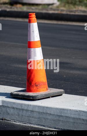 Vertikale Aufnahme eines orangen Verkehrskegels bei Neubauten. Stockfoto