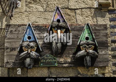 Vogelhäuser, die an einer Berghütte im Isergebirge in Polen aufgehängt wurden. Alte handgefertigte Vogelkisten, die wie Zwerge aussehen Stockfoto