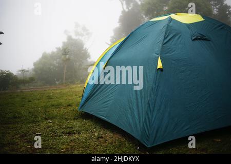 Blaues und gelbes Zelt auf einem Feld nach Regen Stockfoto