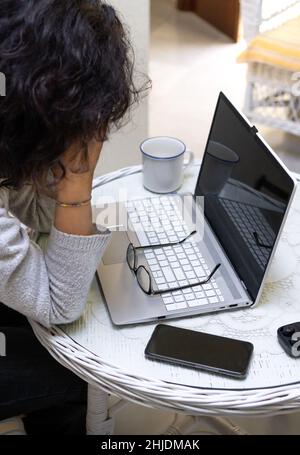 Erschöpfte Freiberuflerin ruht sich während der Arbeit mit einem Laptop zu Hause aus. Stockfoto