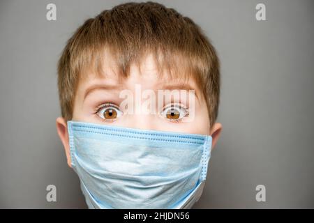 Offene Augen überrascht Kind in Gesichtsmaske Kind schockiert Junge erstaunt oder zurück zur Schule offline lernen. Erstaunt Kind überrascht Junge trägt Maske Kind schockiert Stockfoto