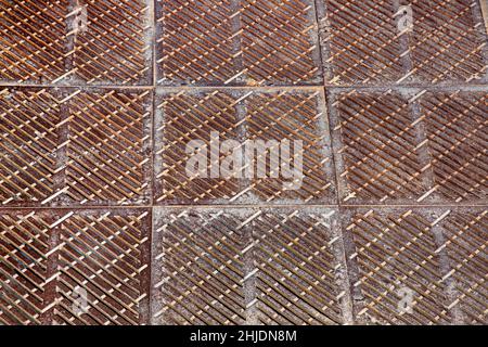 Altes rostiges, quadratisches Drainagerost, die Oberfläche des Sturmsystems auf dem Boden aus der Nähe. Stockfoto