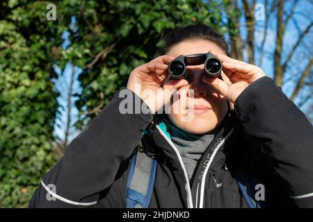 Person Vogelbeobachtung mit Fernglas an einem kalten sonnigen Tag Stockfoto