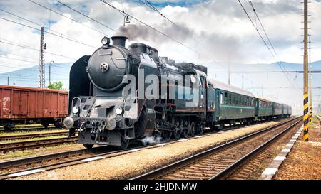 Zug mit einer Dampflokomotive, die zum Bahnhof kommt. Stockfoto