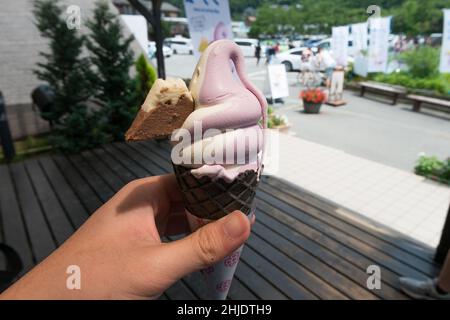Nahaufnahme von weißem und violettem Softeis mit einem Cookie in Form eines Berges eingebettet Stockfoto