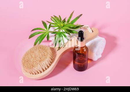 Flaschen aus schwarzem Glas ohne Markennamen mit kosmetischem Öl und ätherischem Cannabisöl und einer hölzernen Gesichtsreinigungsbürste mit natürlichen Borsten. Natürliche Hautpflege Stockfoto