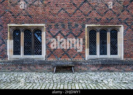 TUDOR Fensterflügel & frühes polychromatisches Tudor-Mauerwerk: Orangerote Ziegelsteine in englischem Kreuzverklebung. Gepflasterte Hof. Hampton Court Palace, London Stockfoto