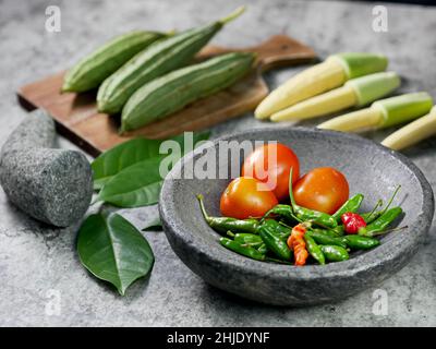 Chilies und Tomaten im Mörser, Rezept für Gemüsekorn und Luffa acutangula mit Tomatensauce. Konzept zur Zubereitung von Speisen. Stockfoto