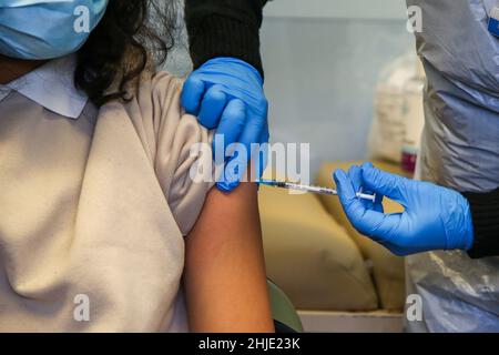 London, Großbritannien. 22nd Januar 2022. Ein Mitarbeiter des Nationalen Gesundheitsdienstes (NHS) verwaltet eine Covid-19-Auffrischungsimpfung an eine Frau in einem Impfzentrum. (Bild: © Dinendra Haria/SOPA Images via ZUMA Press Wire) Stockfoto